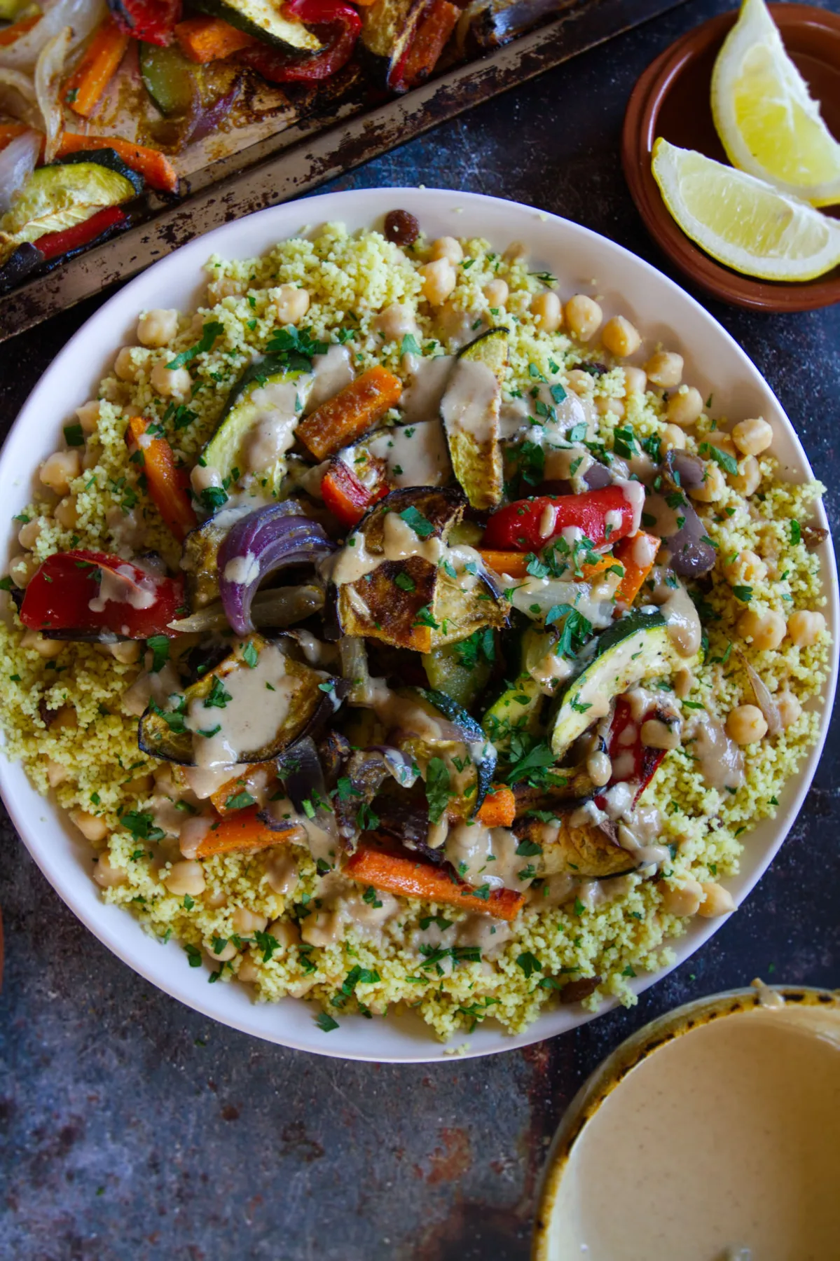 A large plate of Moroccan couscous with roast veggies and drizzled with a tahini dressing.