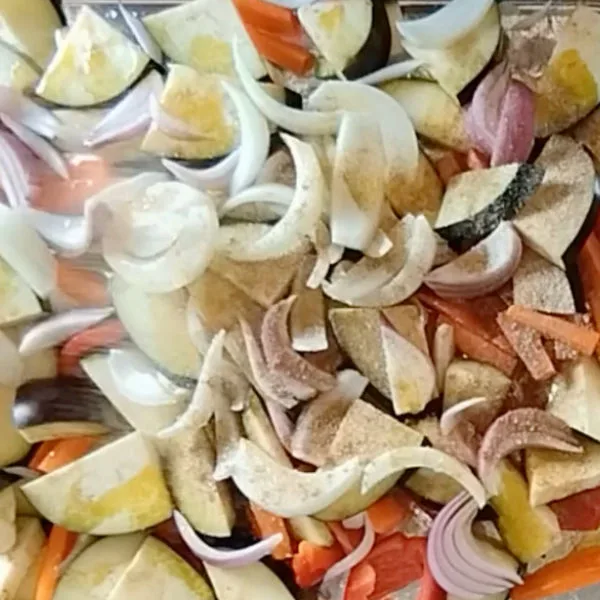 Mediterranean spices are added to a tray of raw vegetable pieces.