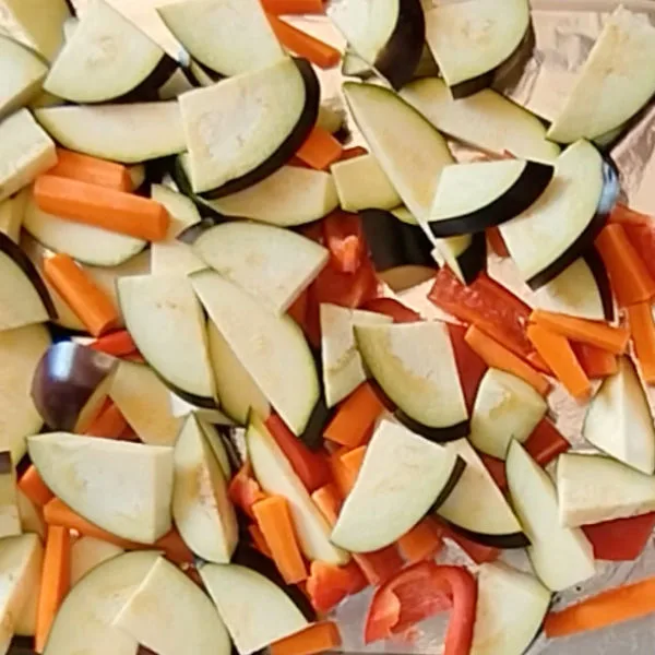 Pieces of raw vegetables are scattered on a large baking tray.