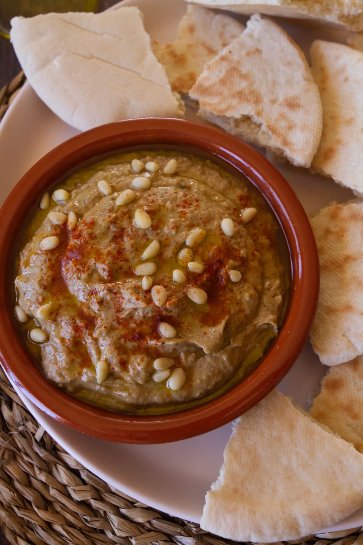 A small bowl of baba ganoush sits beside some pita bread.