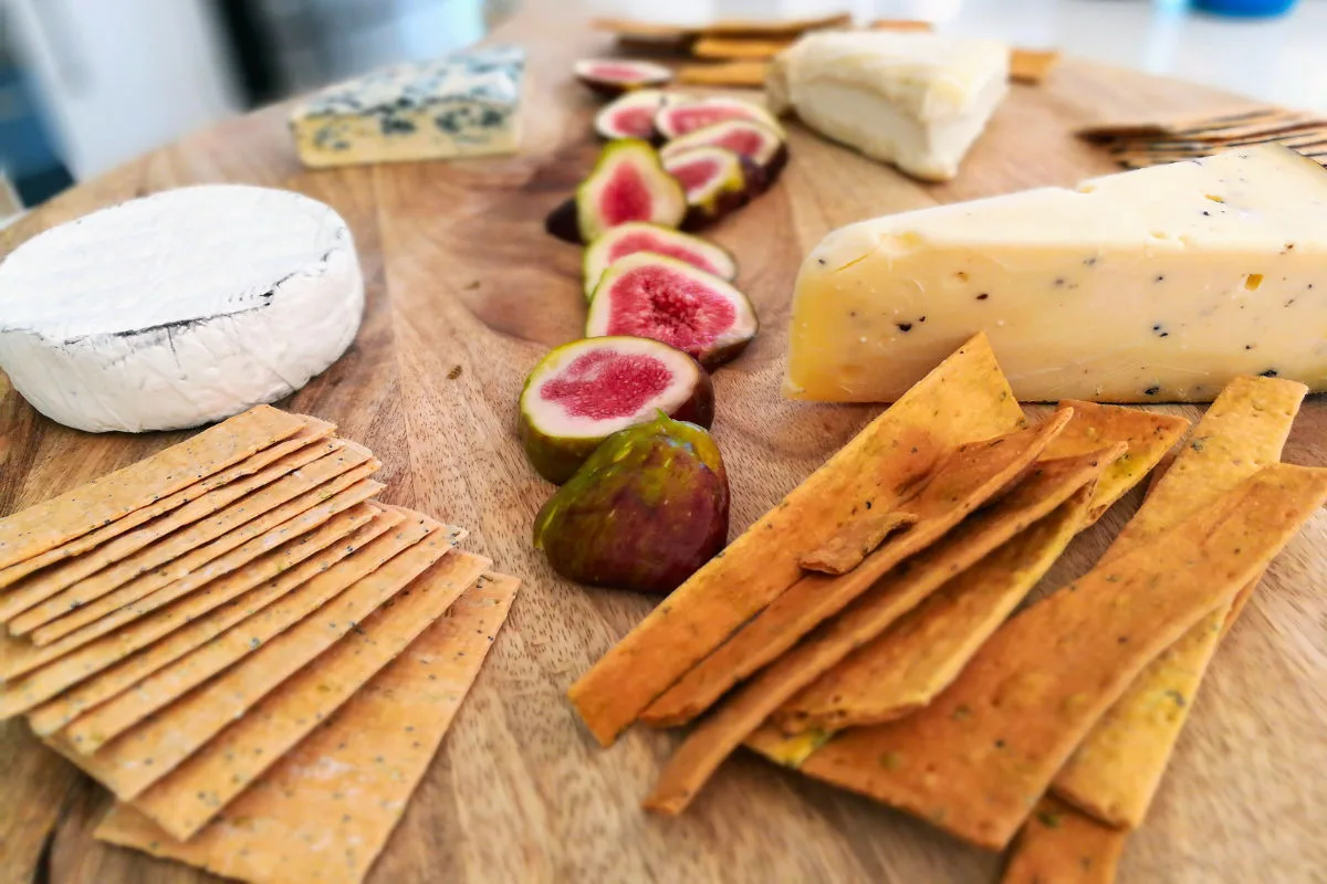 A cheese board with some fresh sliced figs, cheese, and crackers.