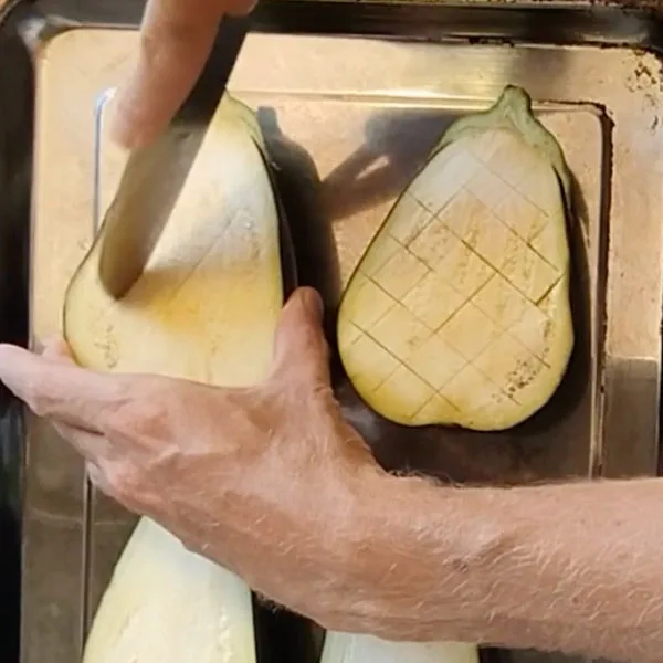 Eggplant is liced in half then the flesh is given a criss-cross cutting pattern.