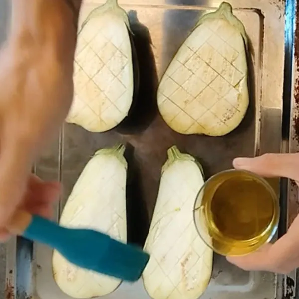 Eggplant halves are glazed with some olive oil.