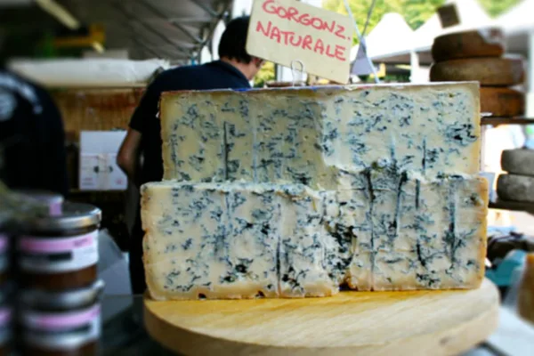 A large block of gorgonzola cheese at a market stall.