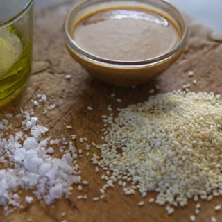 Ingredients to make tahini are laid out on a chopping board.