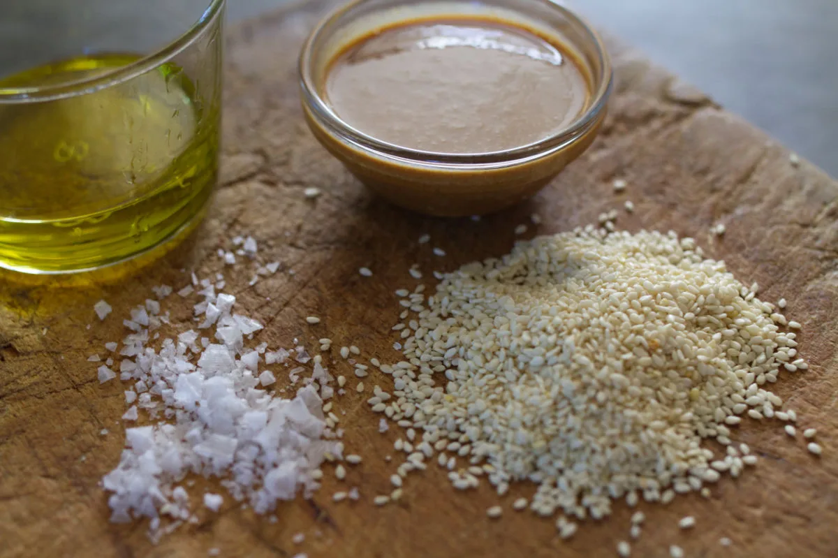 Ingredients to make tahini are laid out on a chopping board. 