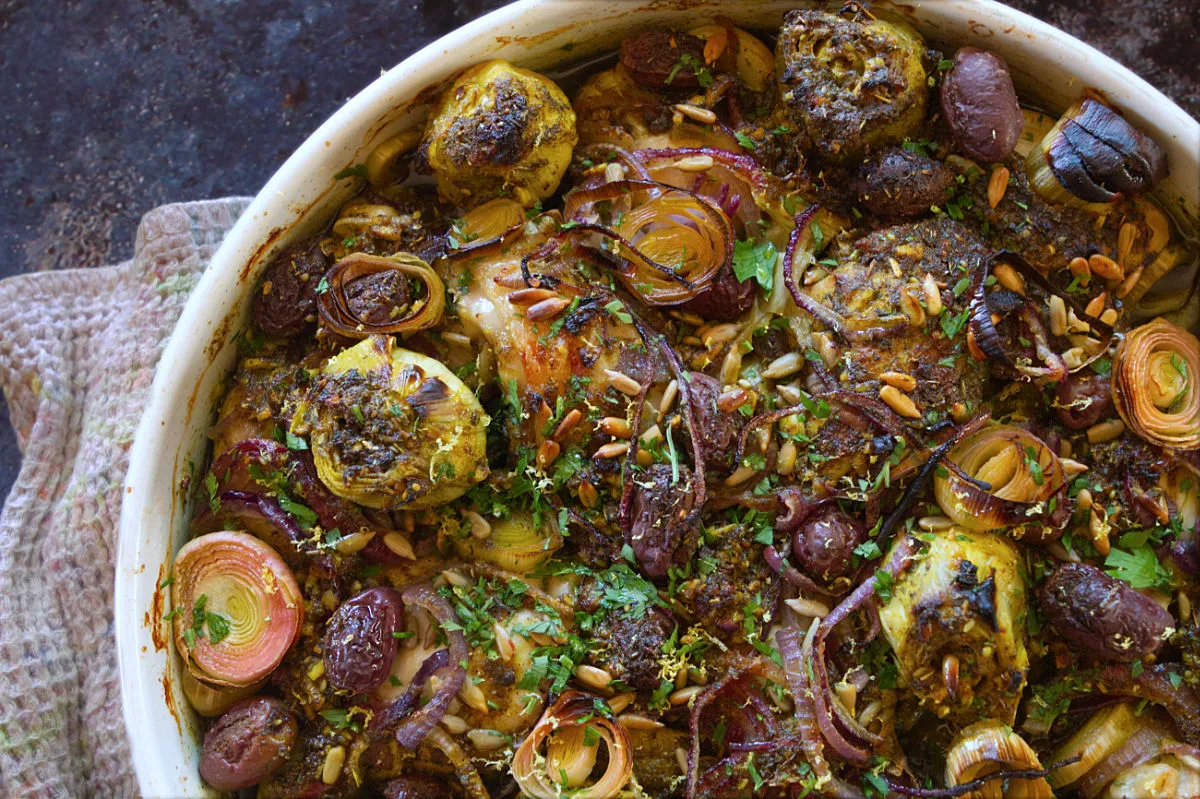 A large dish of Za'atar chicken with leeks, and roasted artichoke hearts.