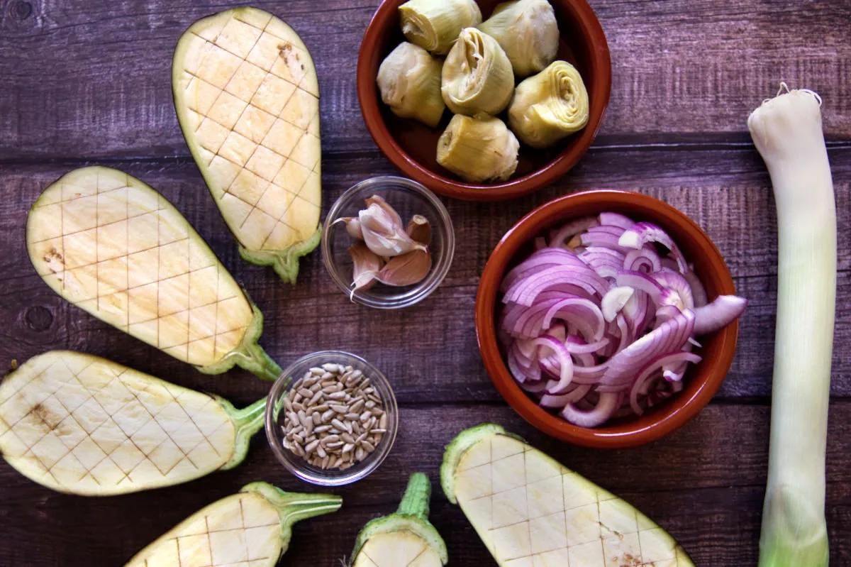 ingredients for making za'atar are laid out beside some halved eggplant, leek, onion, and artichoke hearts.