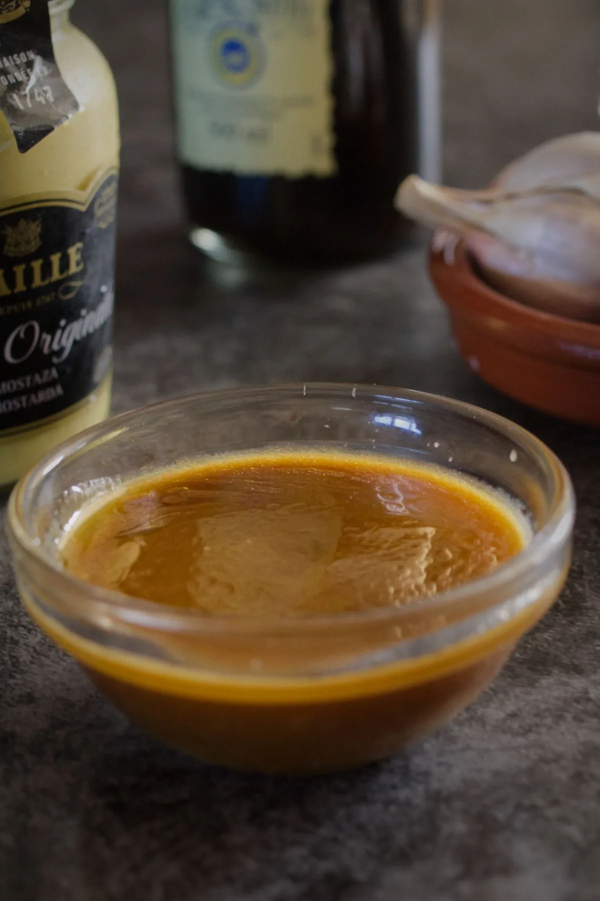 Homemade Balsamic Vinaigrette sits beside some olive oil, balsamic vinegar, and garlic.