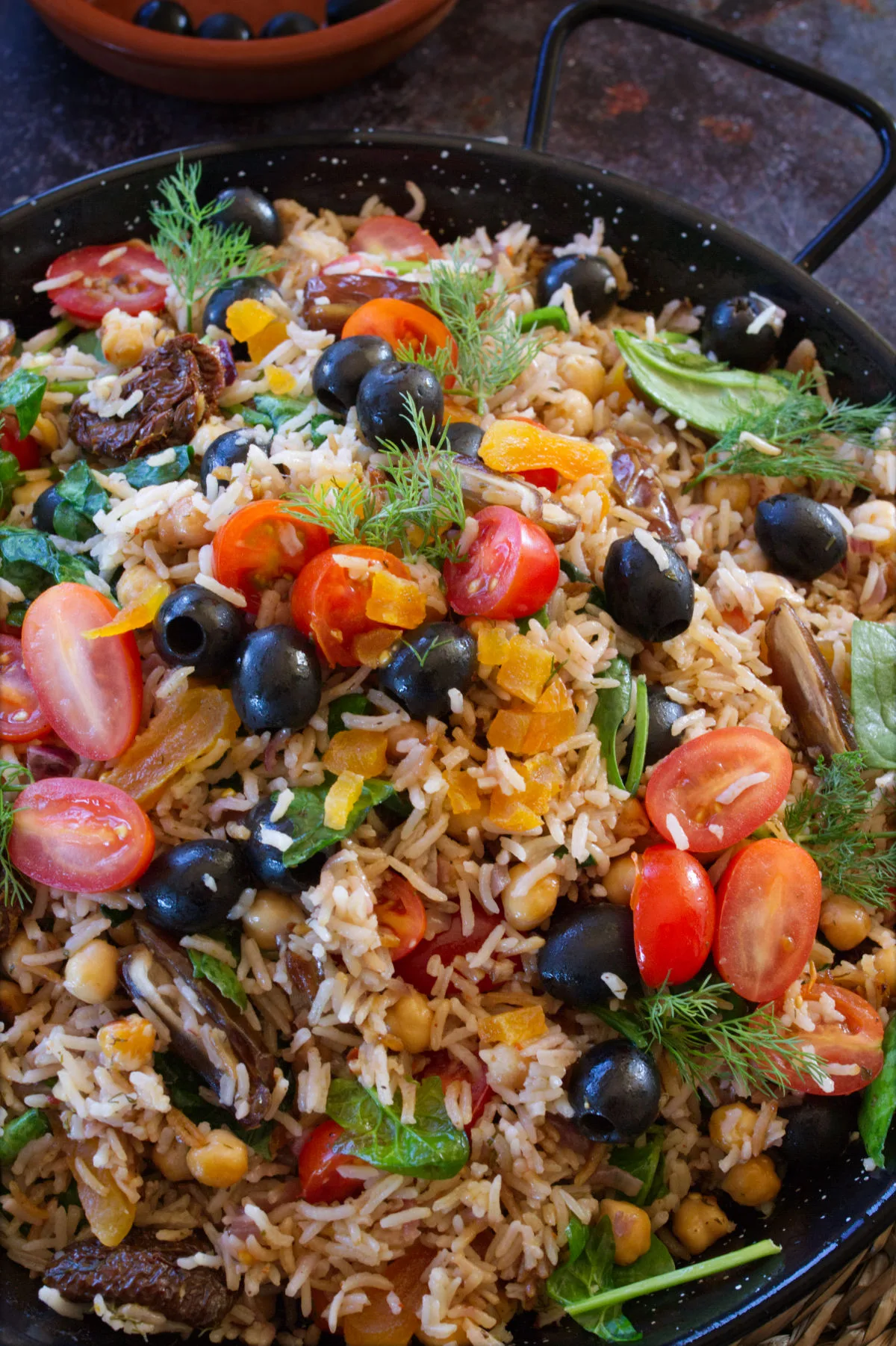 A large pan of Mediterranean Rice garnished with black olives and fresh parsley.