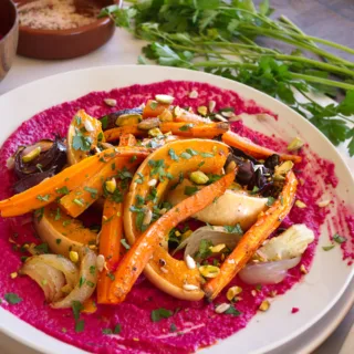 A plate of roasted vegetables served with beetroot and yogurt dip.
