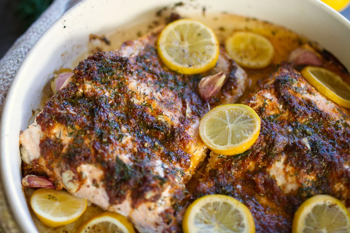 A large baked salmon fillet covered with a lemon, garlic, and dill sauce. 