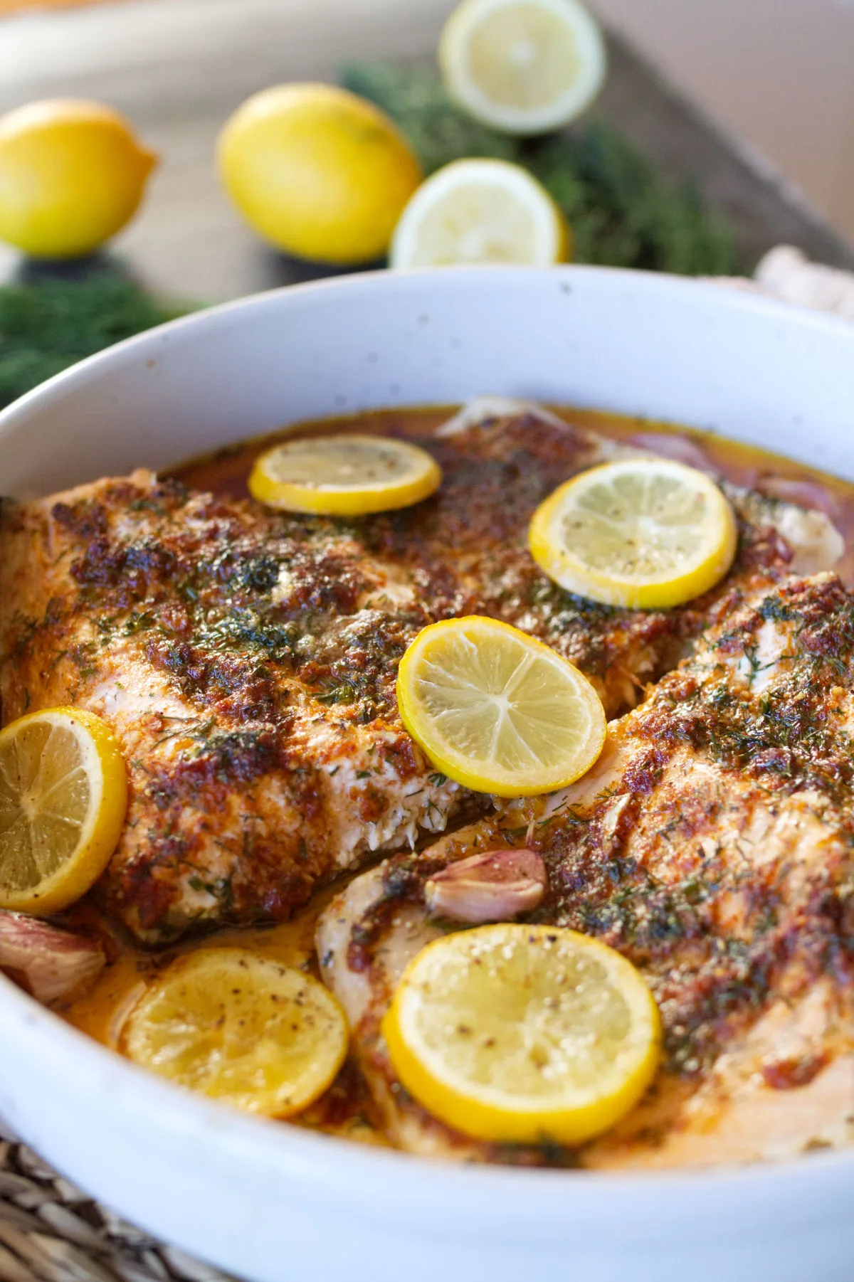A large casserole dish of salmon with lemon, garlic, and fresh dill.