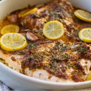 A large baked salmon fillet covered with a lemon, garlic, and dill sauce.