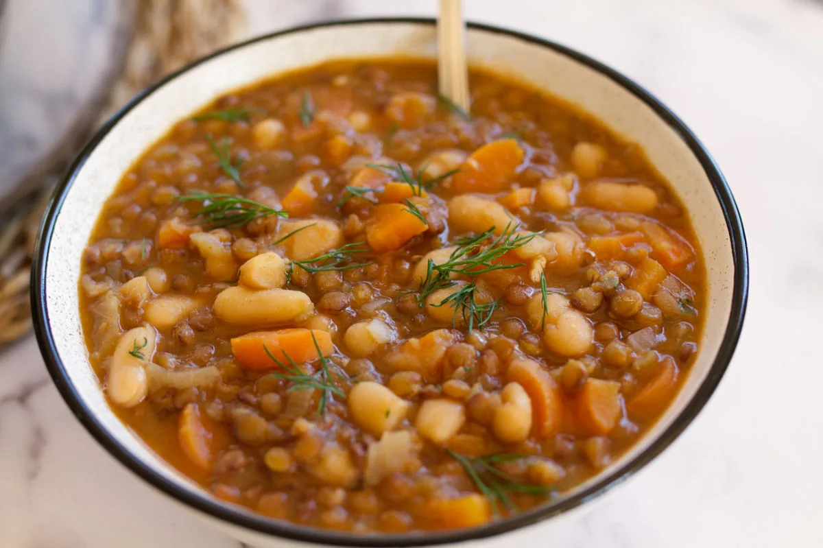 A bowl of vegan Mediterranean Lentil stew sits with a spoon.