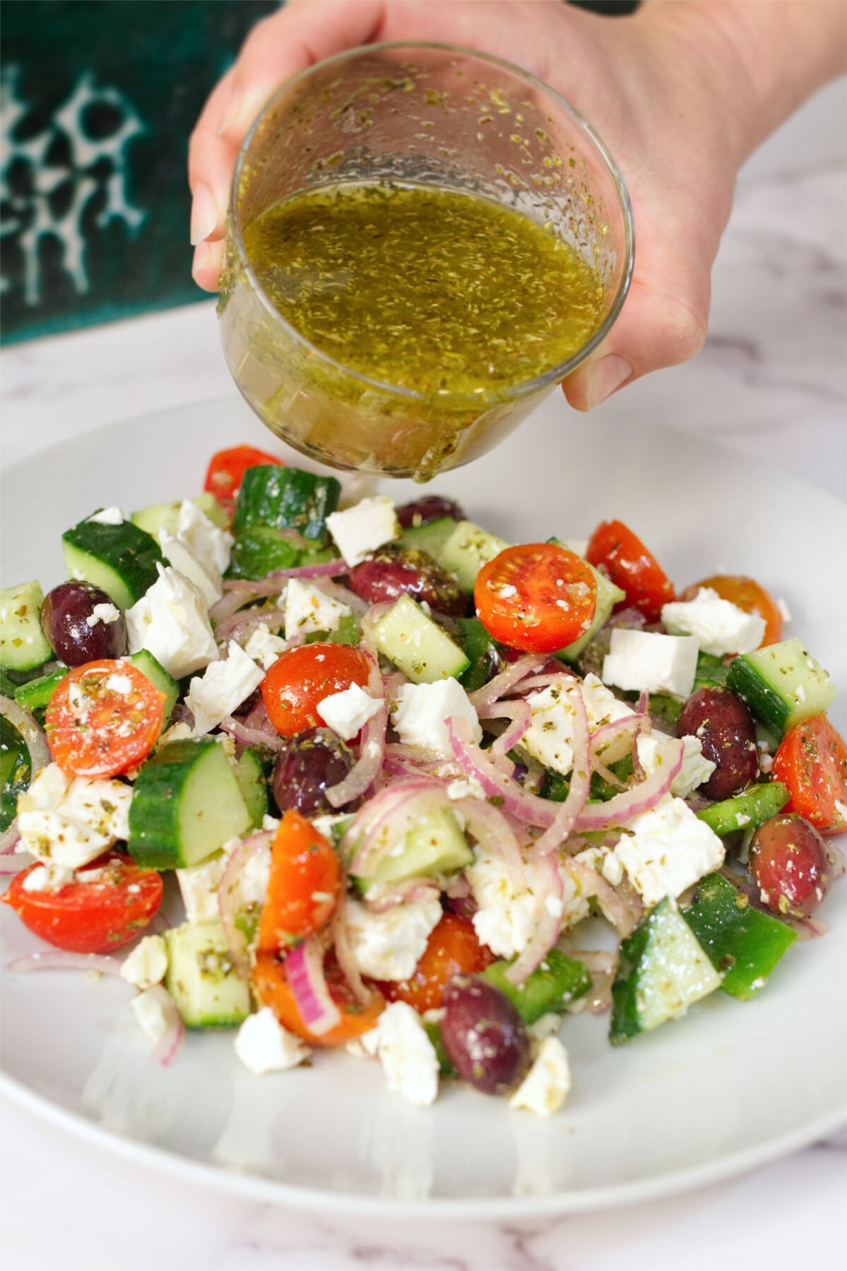 A bowl of Greek salad with some dressing drizzled over it. 