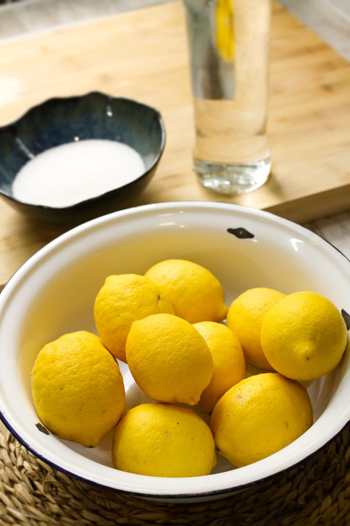 a bowl of lemons sits beside some vodka liqueur and sugar.