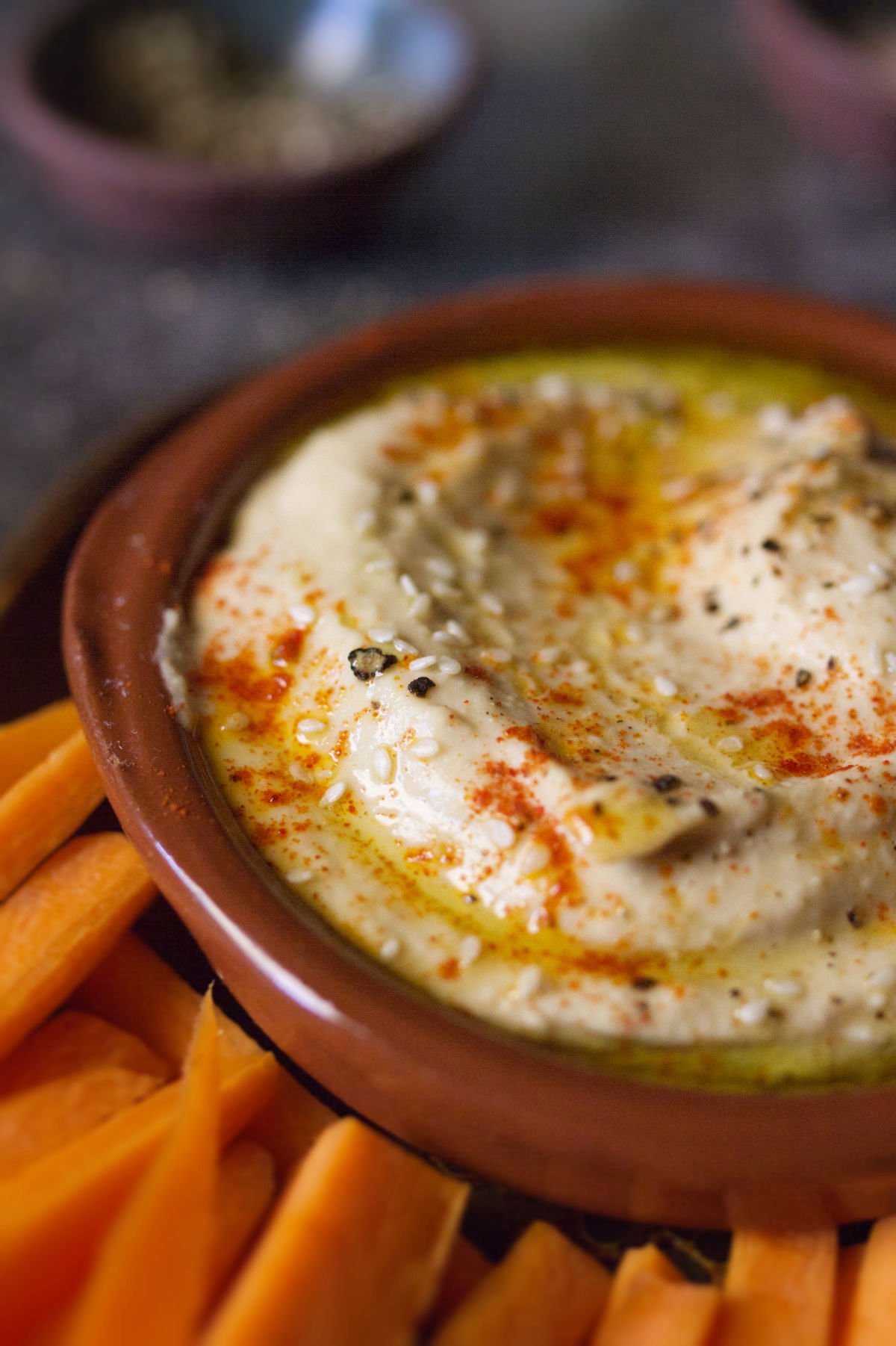 A bowl of Mediterranean hummus beside some carrot sticks