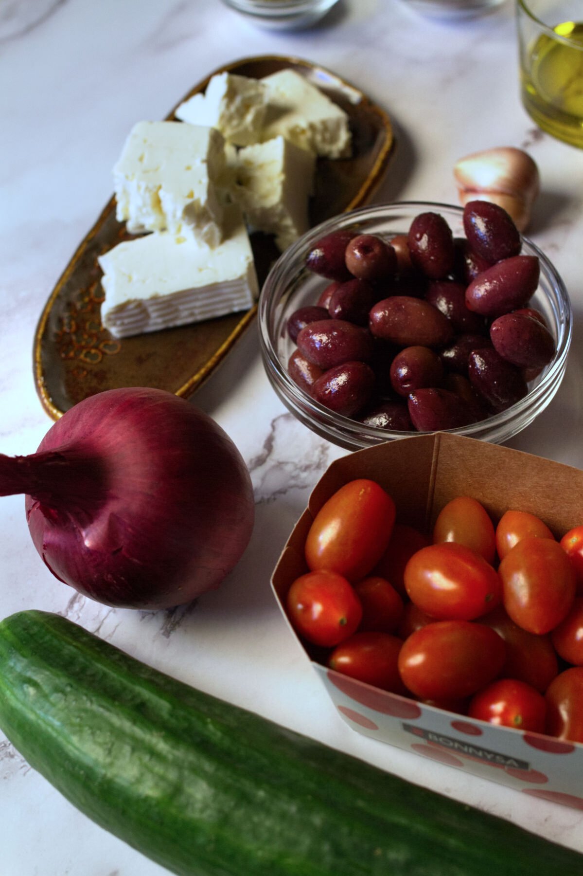 salad ingredients sit beside some Kalamata olives and feta cheese.