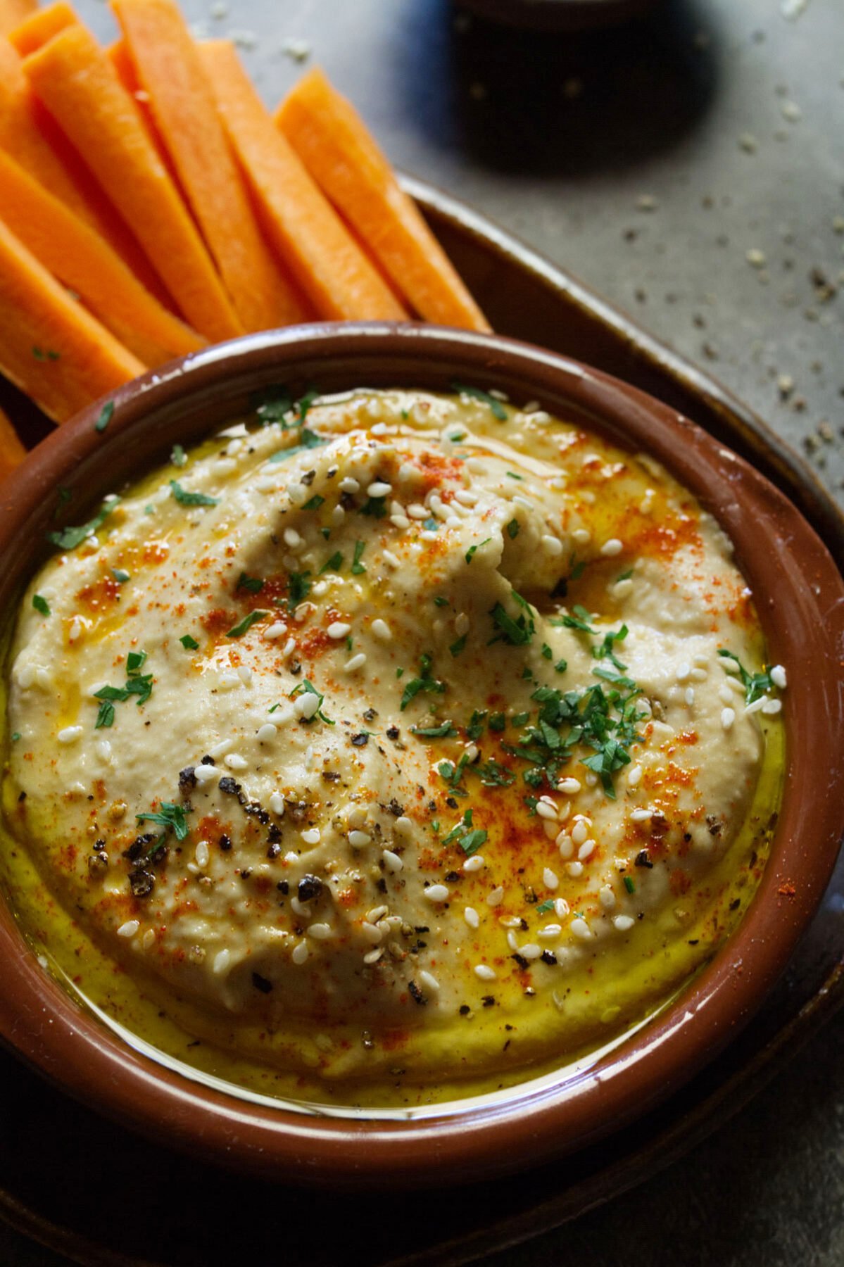 A bowl of Mediterranean hummus beside some carrot sticks