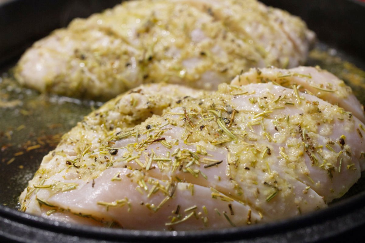 two marinated chicken breasts cook in a skillet