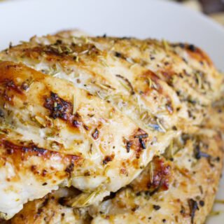 A cooked marinated chicken breast sits in a bowl.