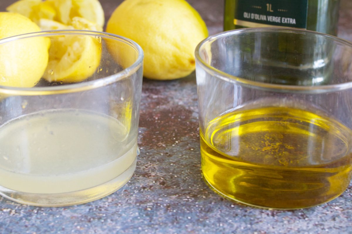 Some lemon juice and olive oil sit beside each other.