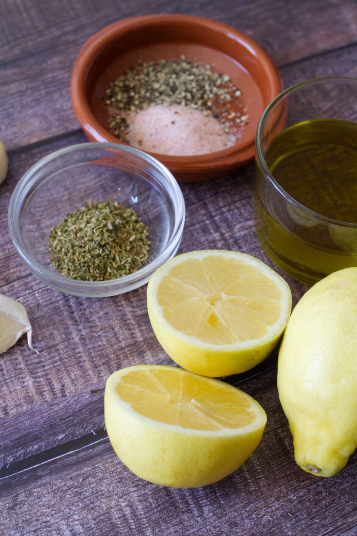 lemons sit beside garlic, herbs, and olive oil. 