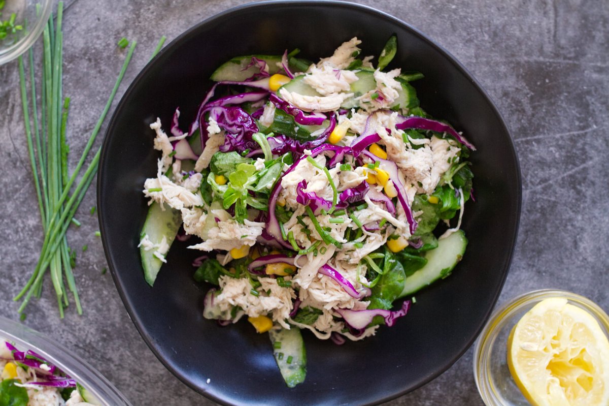 A bowl of shredded chicken salad sits beside a fork.