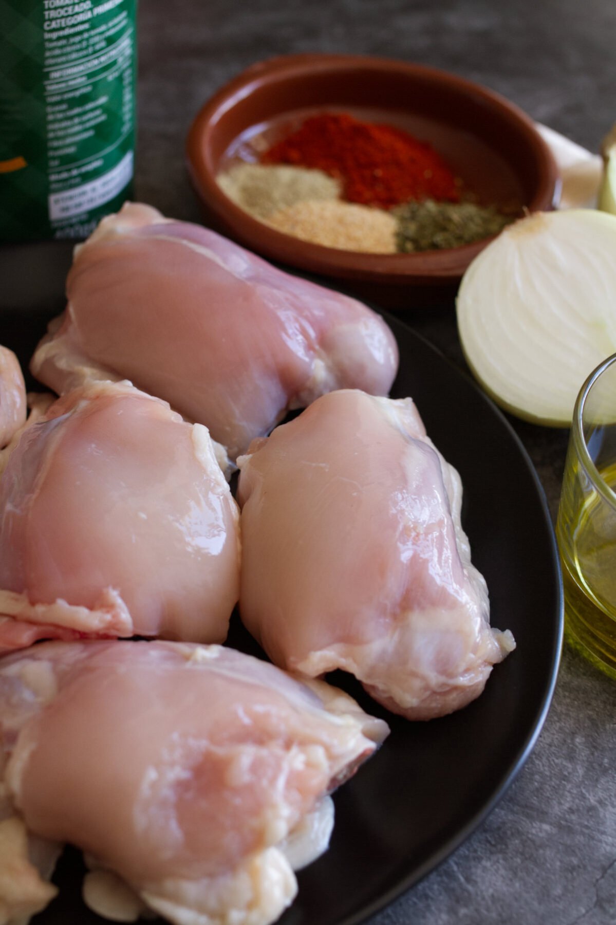 chicken thighs sit beside Spanish seasoning mix and onions