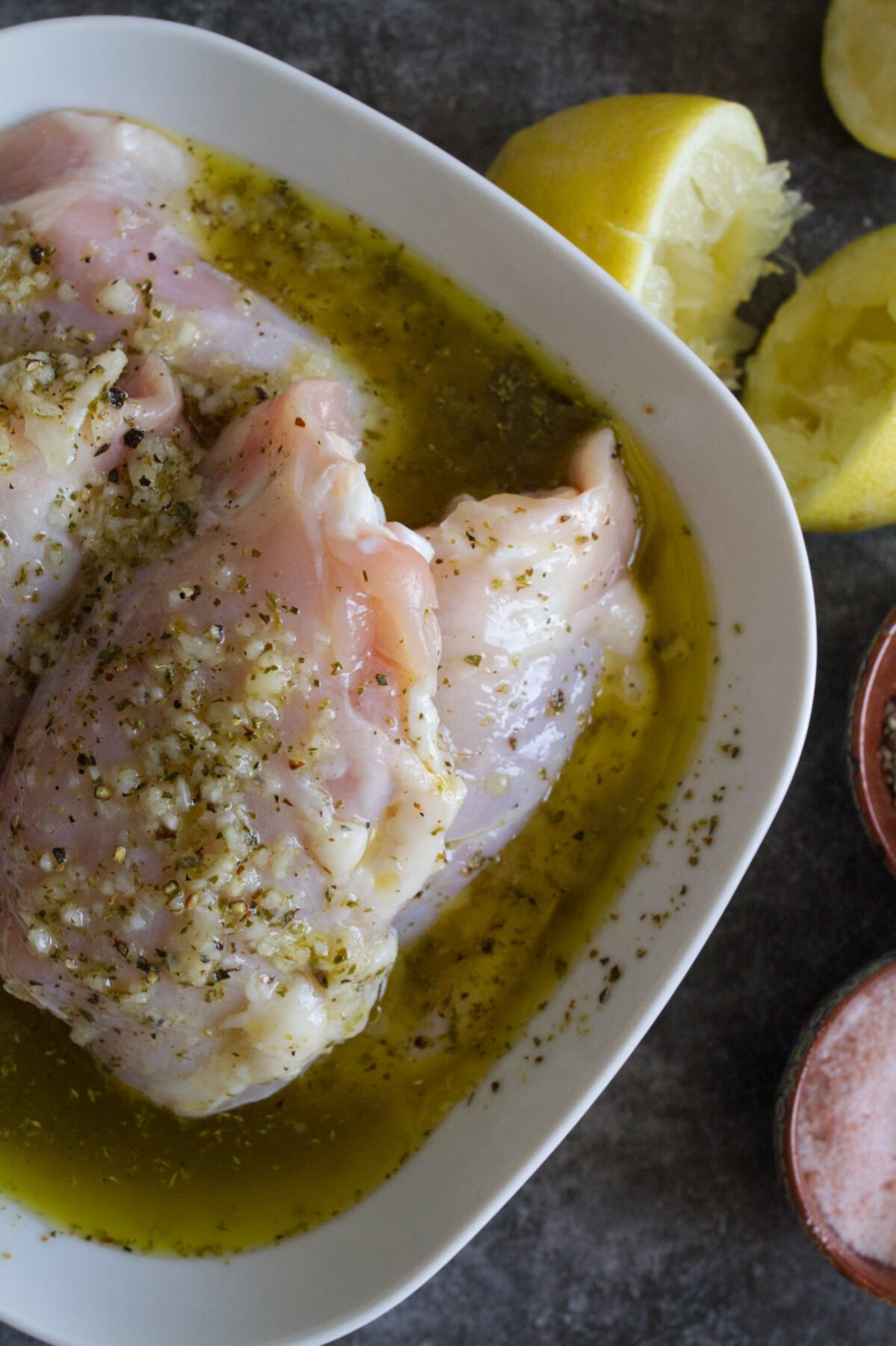 pieces of chicken sit coated with a Mediterranean marinade in a bowl