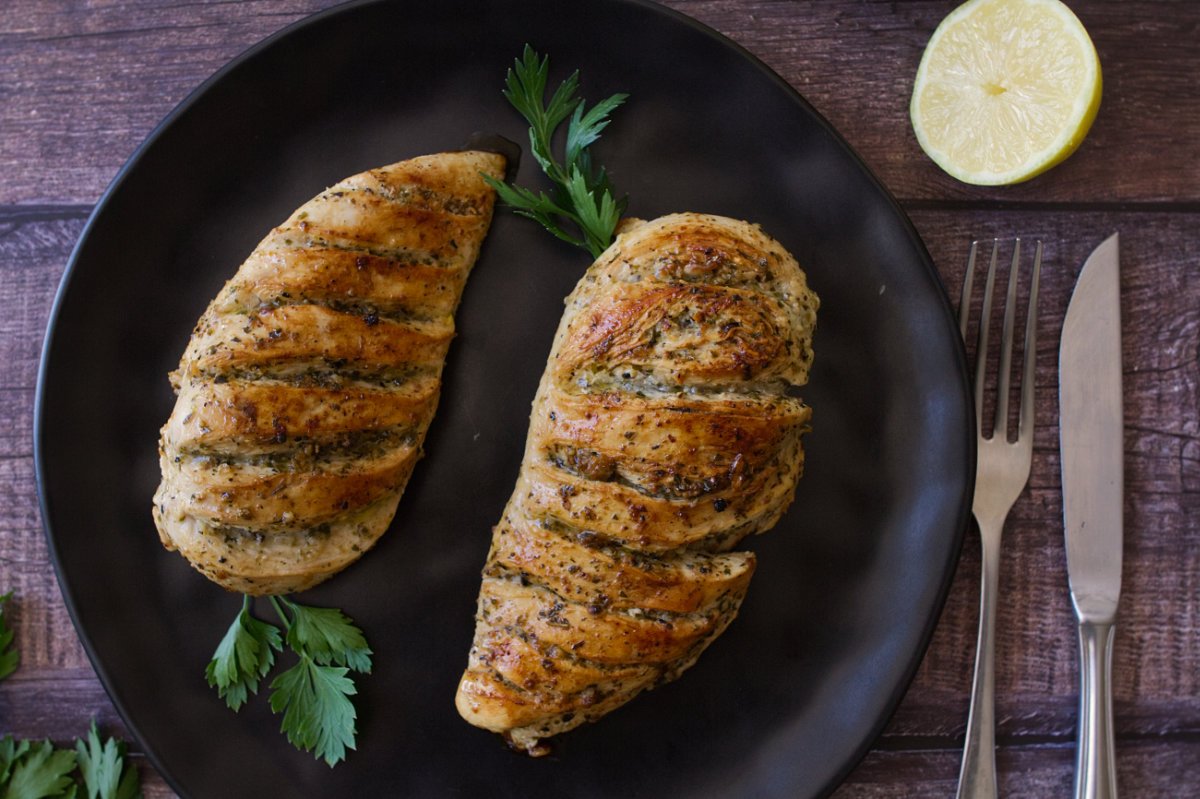 Grilled lemon herb chicken breasts sit on a plate