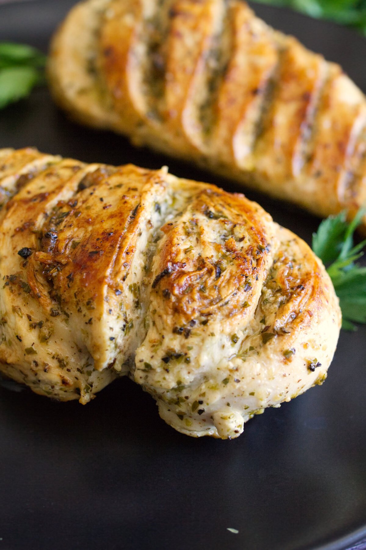 A grilled lemon herb chicken breast sits on a plate