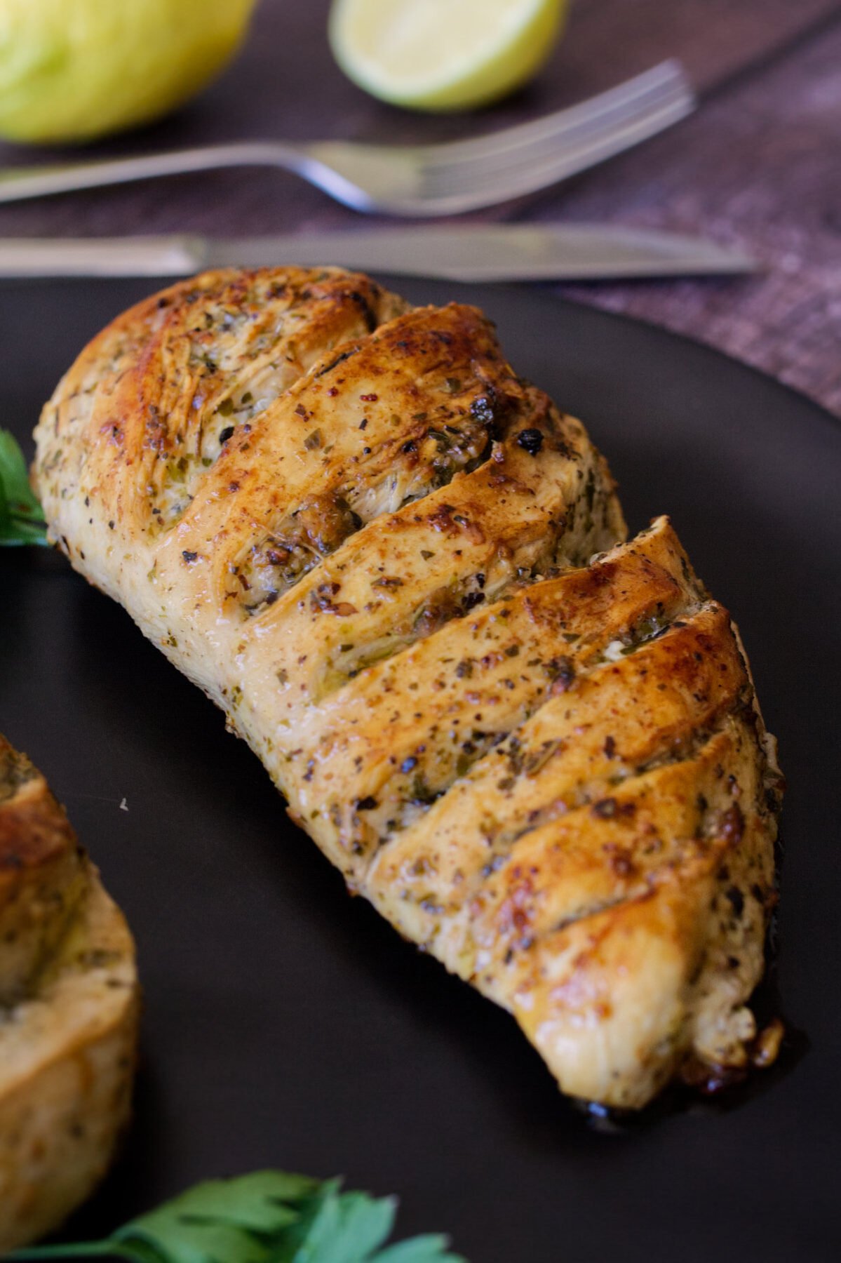 A grilled lemon herb chicken breast sits on a plate