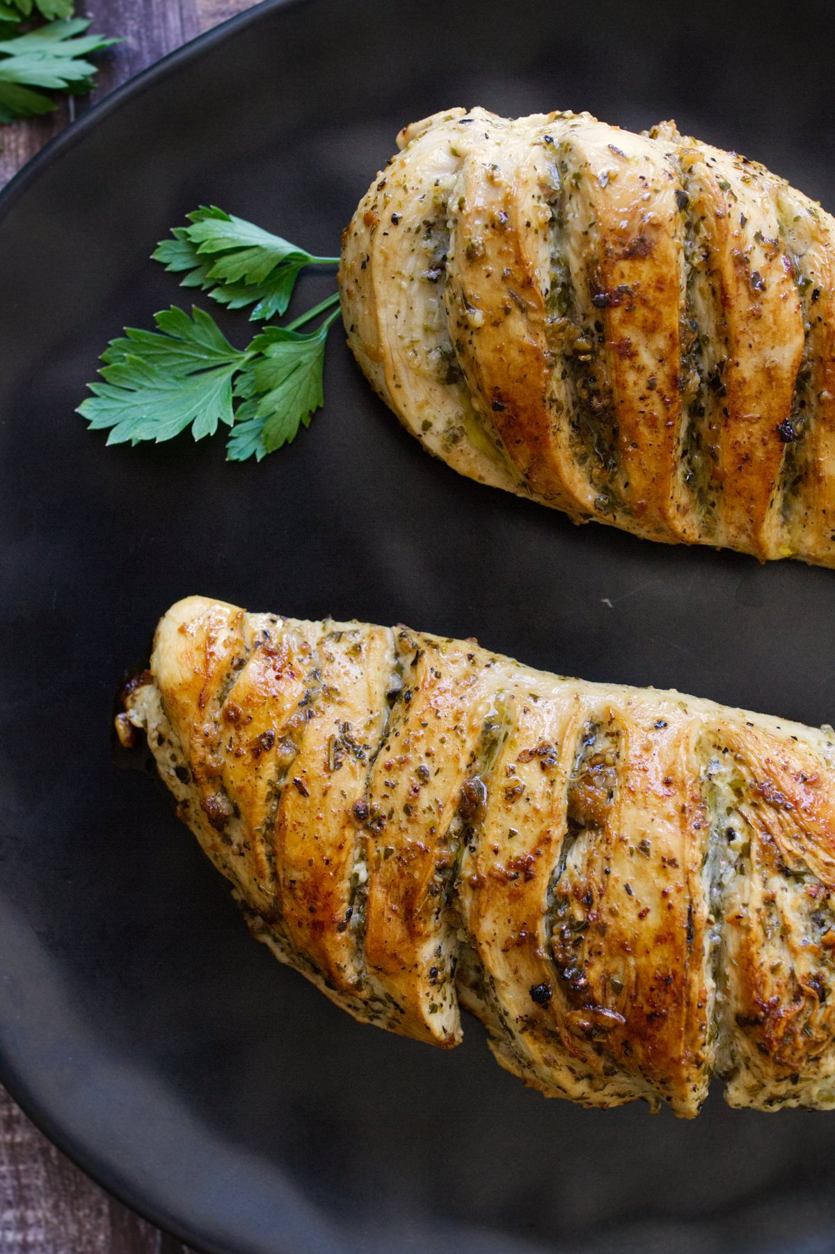 A grilled lemon herb chicken breast sits on a plate