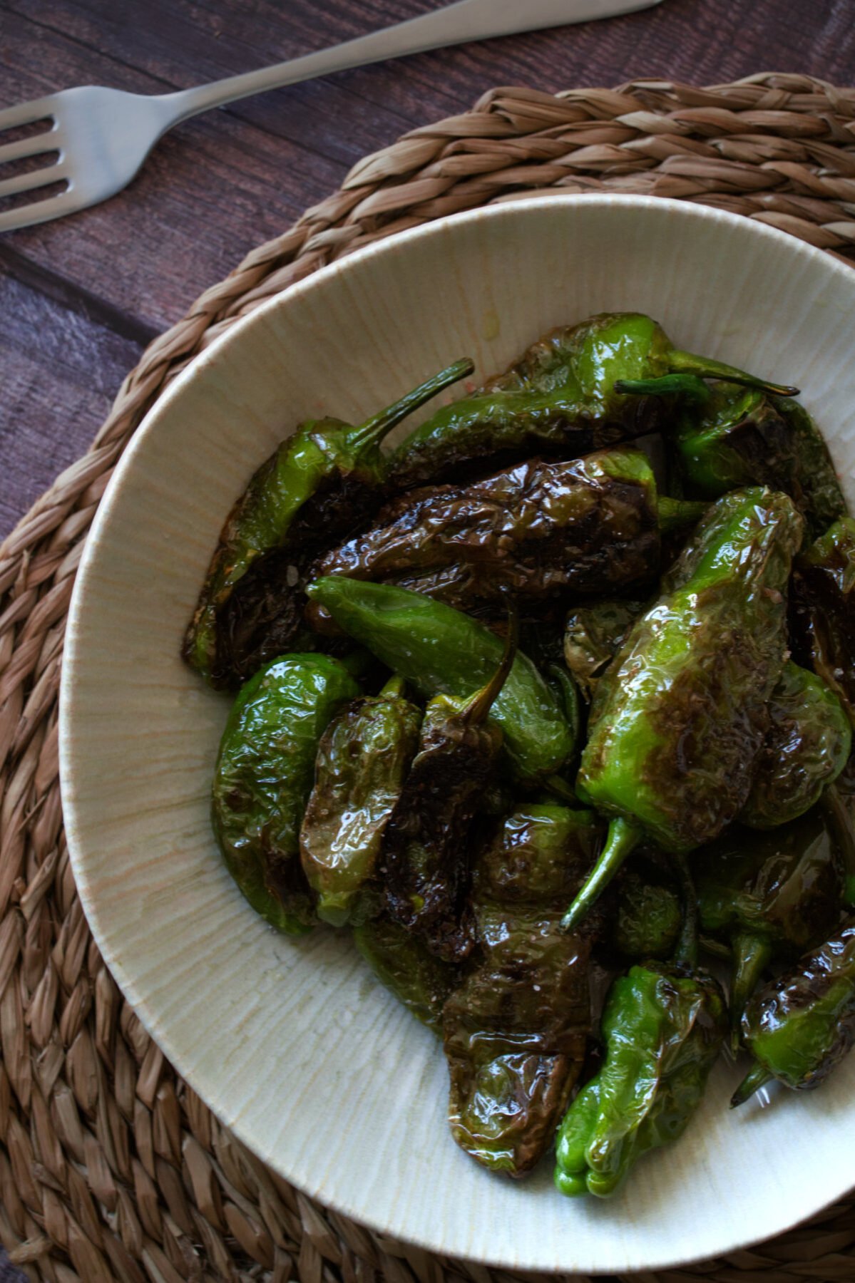 A bowl of cooked Spanish padron peppers.