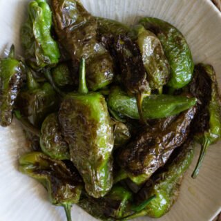 A bowl of cooked Spanish padron peppers.