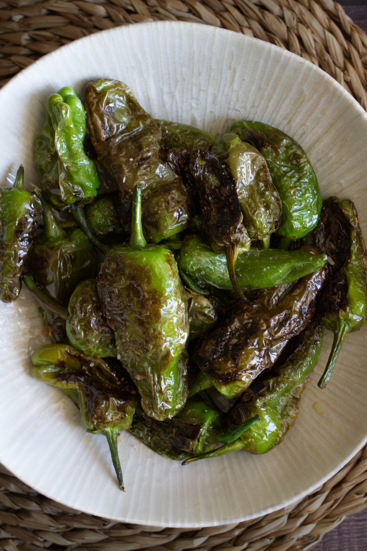 A bowl of cooked Spanish padron peppers.