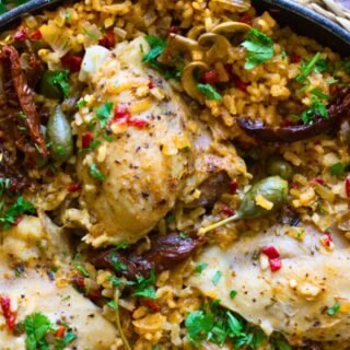 A large pan of Italian Chicken thighs with lots of rice.