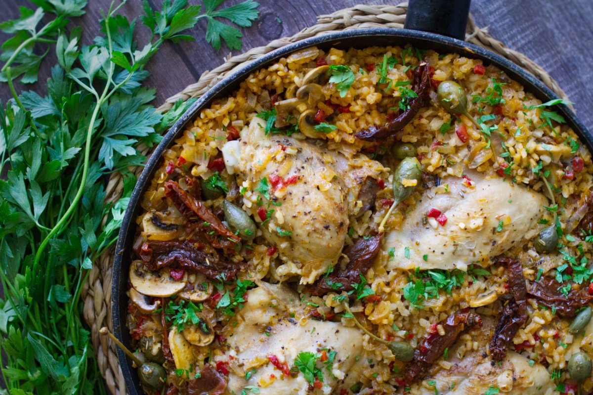 A large pan of Italian Chicken thighs with lots of rice.