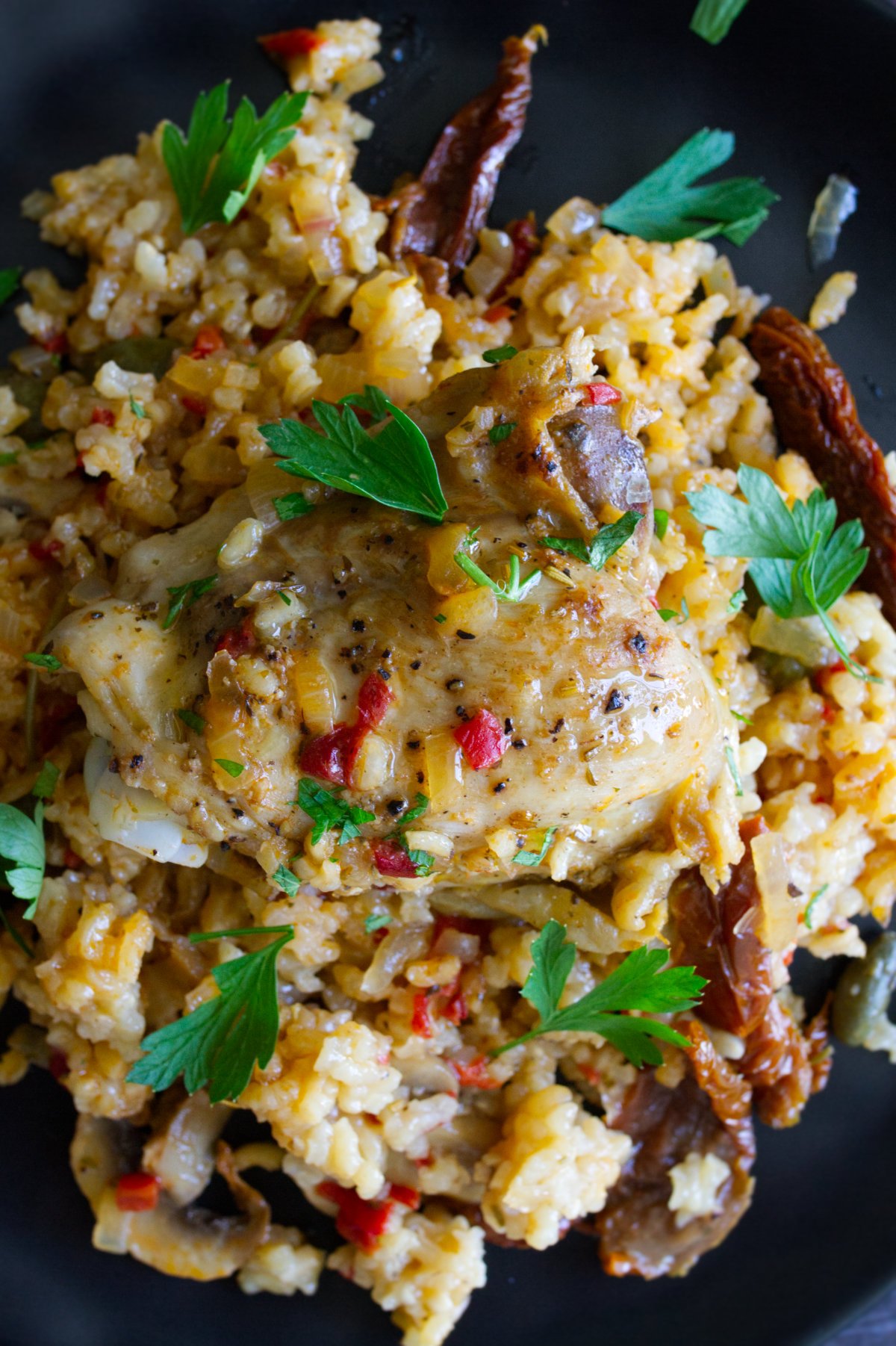 A large pan of Italian Chicken thighs with lots of rice.