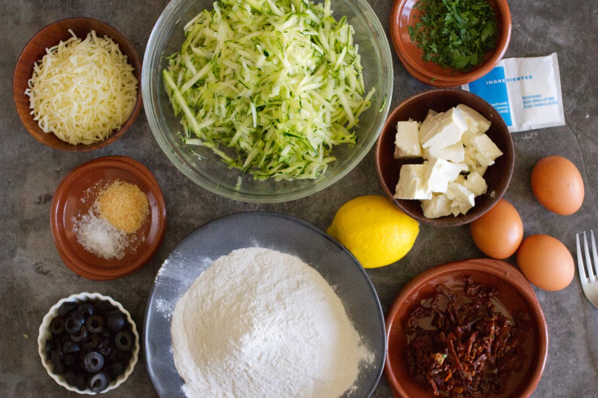 Ingredients to make Mediterranean zucchini bread are laid out in bowls