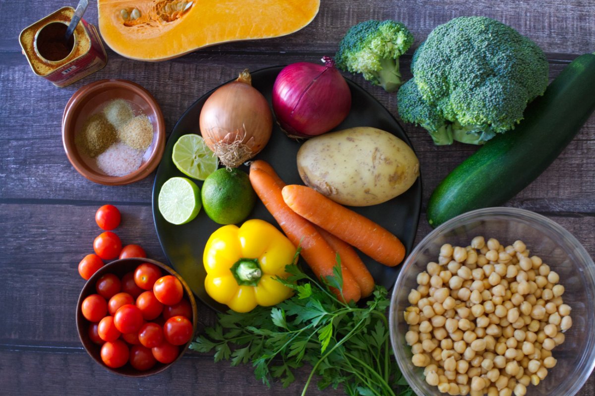 A selection of raw veggies next to a bowl of chickpeas