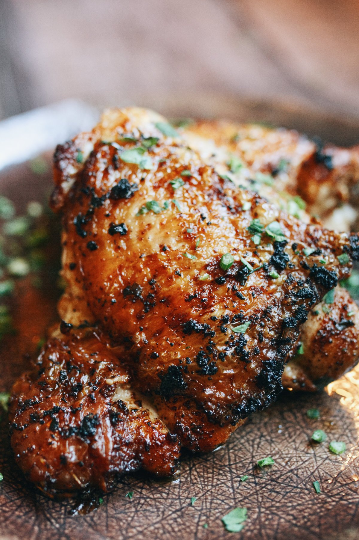 A spicy paprika chicken thigh sits on a plate with some parsley as garnish