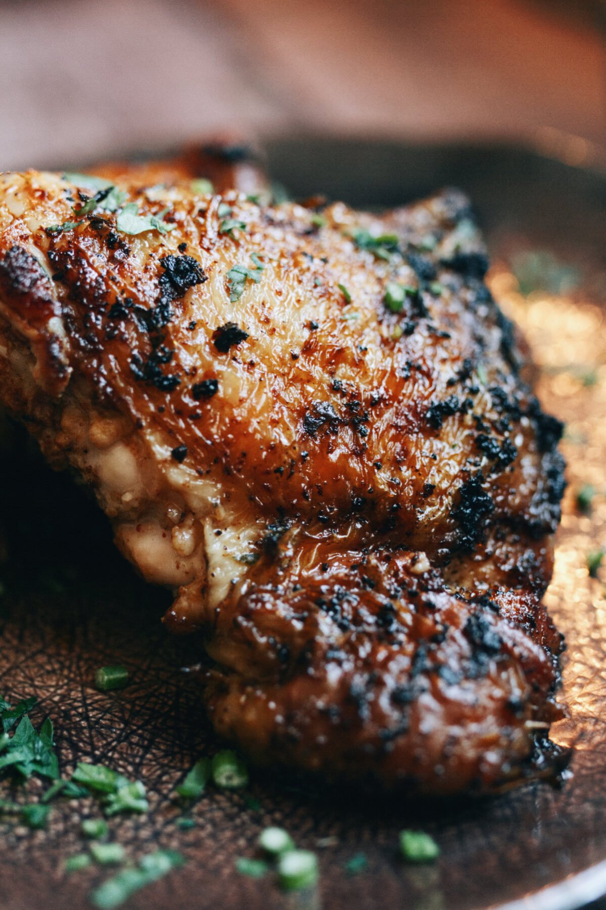 A spicy paprika chicken thigh sits on a plate with some parsley as garnish