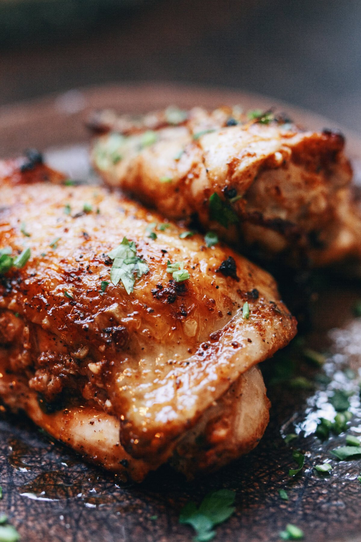 A spicy paprika chicken thigh sits on a plate with some parsley as garnish