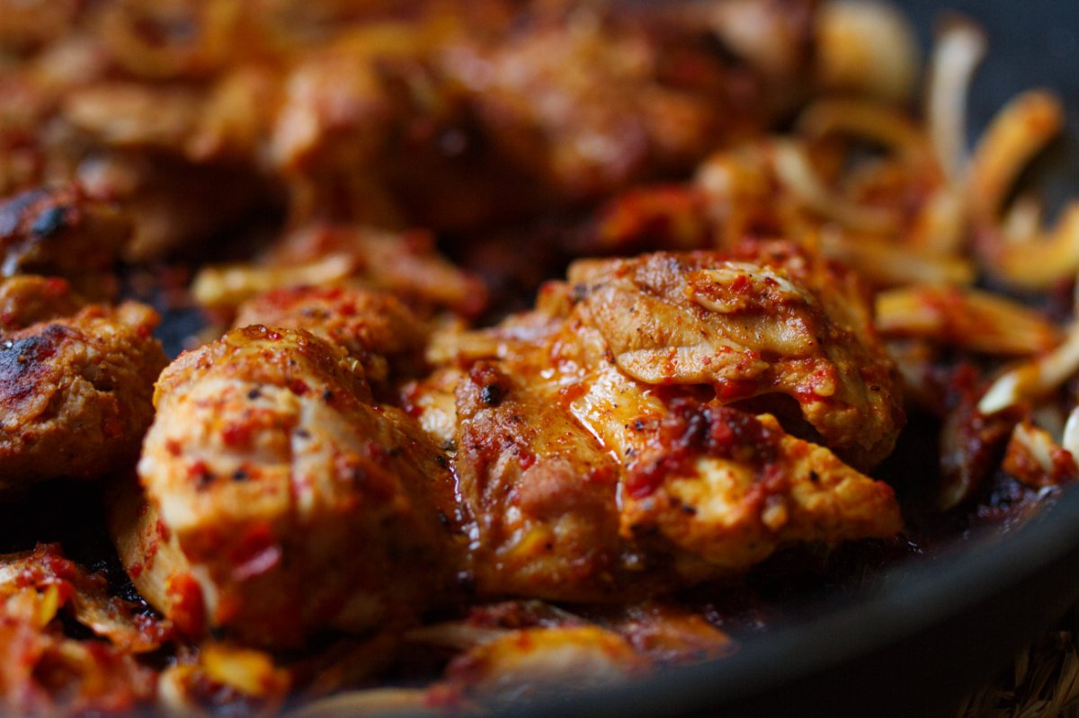 a close shot of some harissa chicken cooked in a pan. 