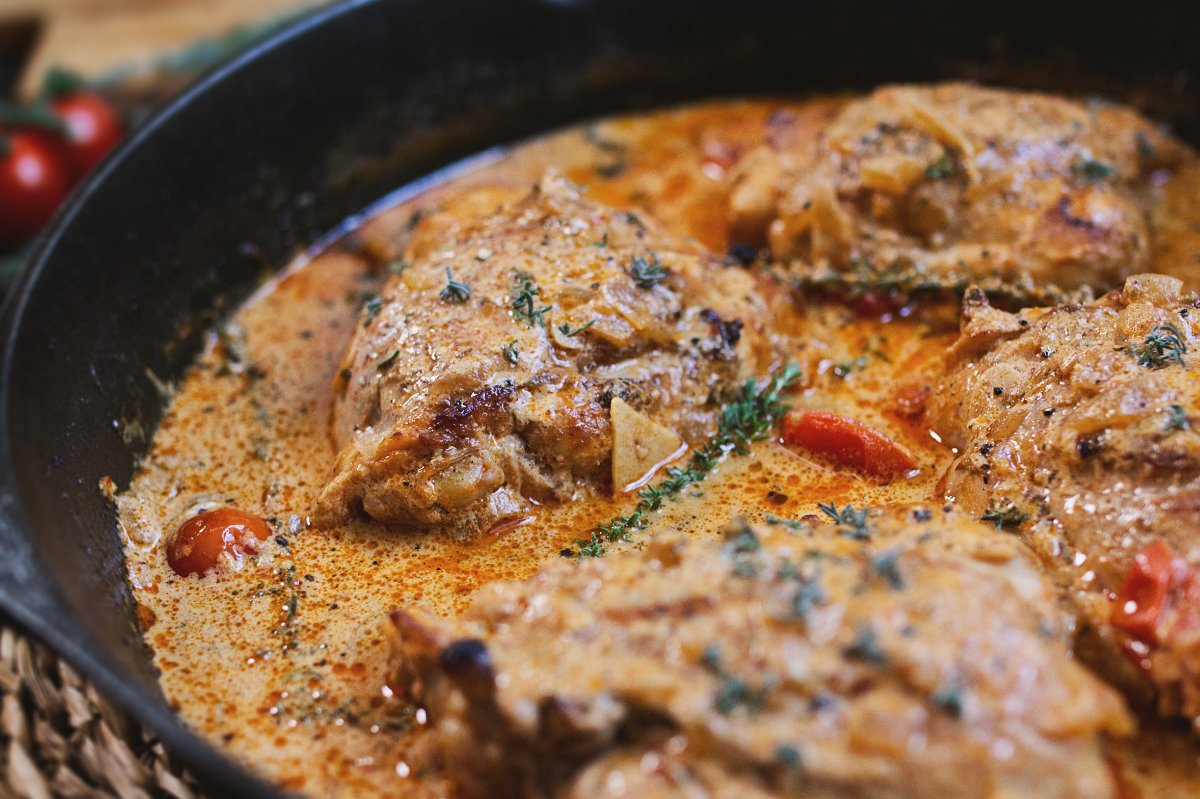 A skillet of creamy Mediterranean chicken thighs garnished with fresh thyme