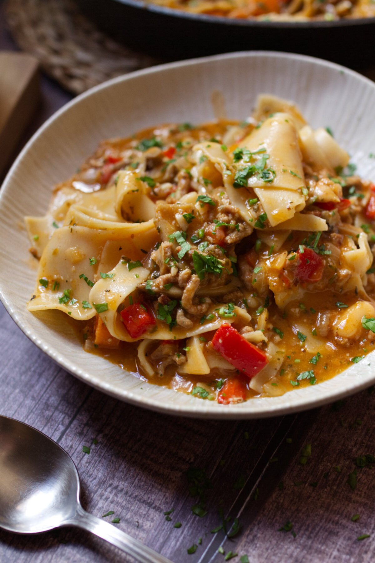 a bowl of lasagna soup sits garnished with fresh basil and parsley