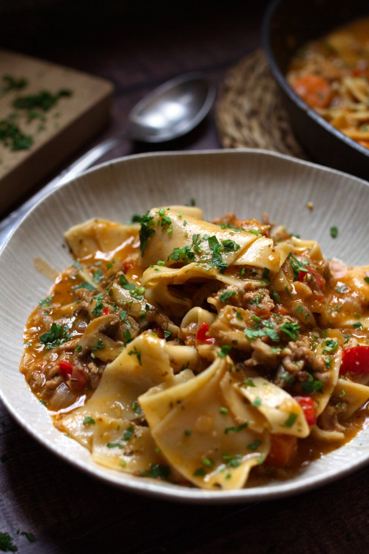 a bowl of lasagna soup sits garnished with fresh basil and parsley